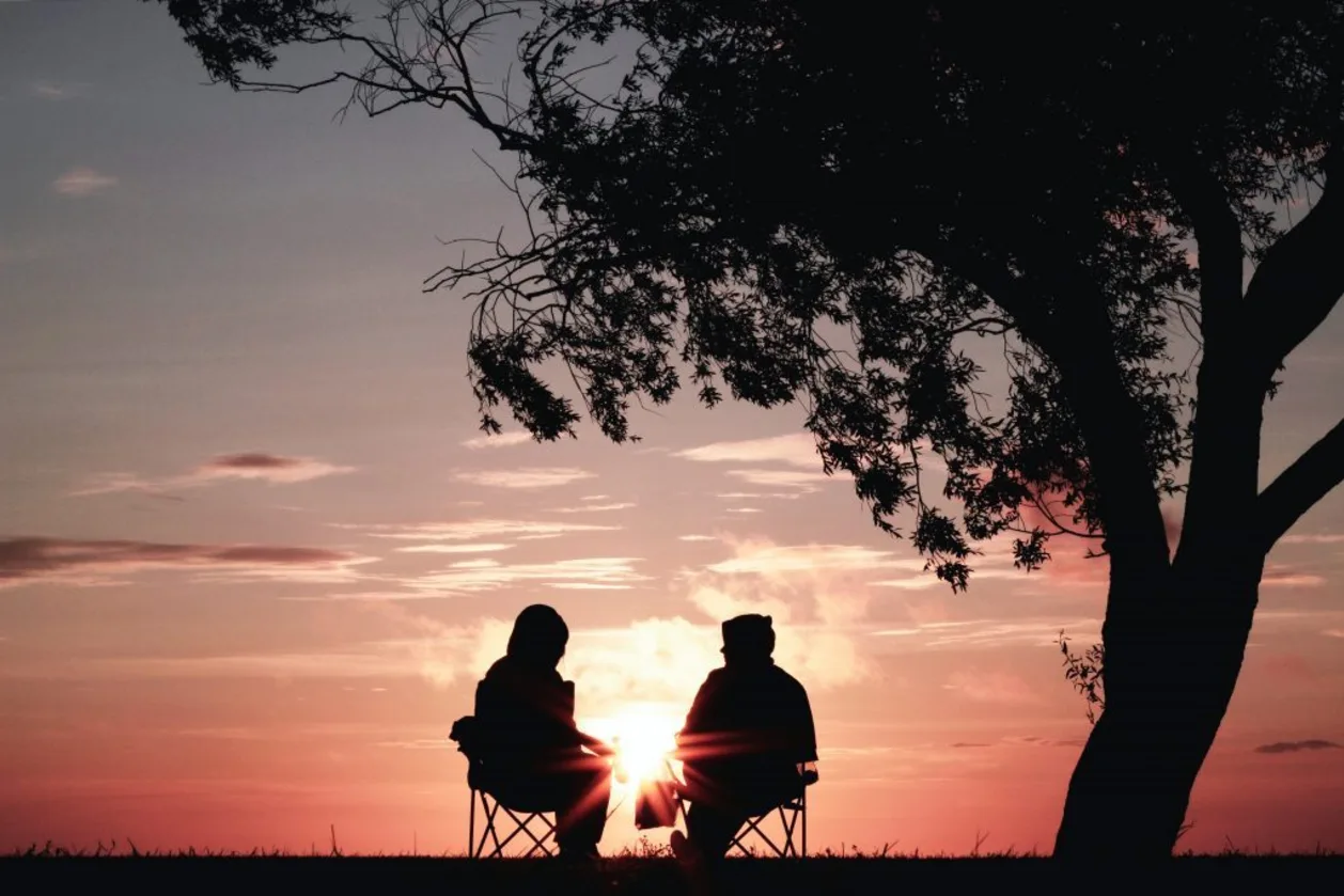 couple sitting under tree at sunset